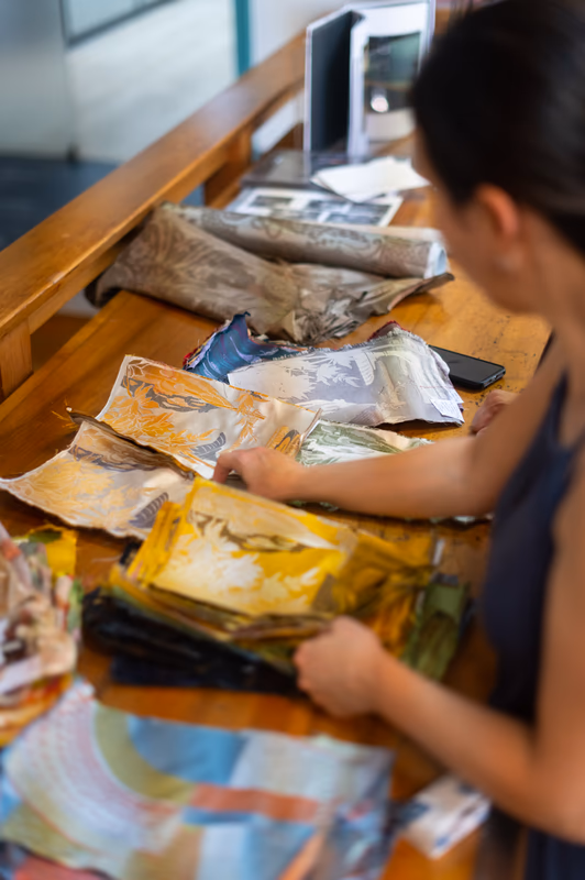 Sabine Verzier consultant des échantillons de tissus colorés sur une table en bois